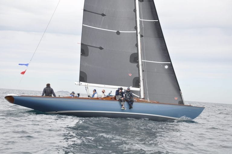 Wooden boat on the water with crew sitting on the side